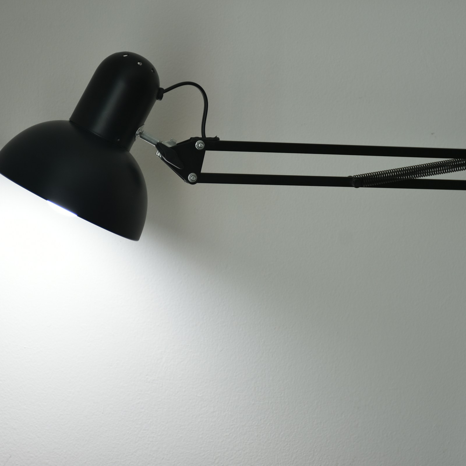 Black adjustable desk lamp illuminating a work surface